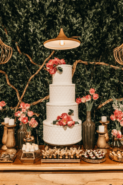 A wedding photographer in Dallas captures a white wedding cake adorned with strawberries and flowers with vases of flowers nearby